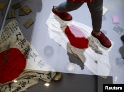 A visitor walks on a glass flooring above Japanese military flags seized by the Chinese People's Liberation Army (PLA) during World War II, at the Museum of the War of Chinese People's Resistance Against Japanese Aggression, in Beijing, China, Sept. 1, 20