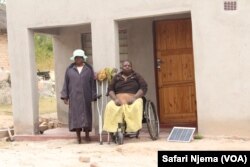 Praxedes Chadambura with her mother-in-law in from of her four-roomed house