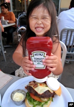 Haley Ho, 6, smiles as she pours Heinz Ketchup on her hamburger at a restaurant in Palo Alto, Calif. (AP Photo/Paul Sakuma)
