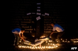 People lift a mock victim during a prayer vigil in support of the families of victims of extra-judicial killings in Manila on April 12, 2017.