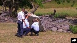 Des gnedarmes français inspectent le fragement de l'aile de l'avion retrouvé jeudi 30 juillet dans l'ile française de la Réunion.