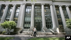 FILE - In this Aug. 1, 2005, image, a bicyclist walks by Harvard University's Langdell Hall, which includes Harvard Law School's library, in Cambridge, Mass. Following an October 2015 talk at Harvard Law School organized by students in the group Justice for Palestine, the international law firm Milbank modified a five-year, $1 million pledge to fund scholarly conferences organized by Harvard Law School students, deciding the 2012 donation from the New York City-based firm should no longer pay for student activities.