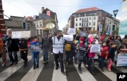An organizer leads children holding signs out of the Molenbeek district during a march against hate in Brussels on Sunday, April 17, 2016.