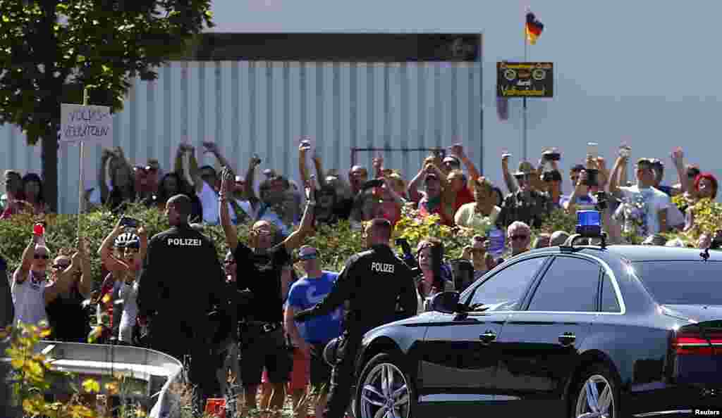 People hold a placard reading &quot;Traitor&quot; as German Chancellor Angela Merkel leaves after her visit to an asylum center in the eastern German town of Heidenau, near Dresden, Aug. 26, 2015.