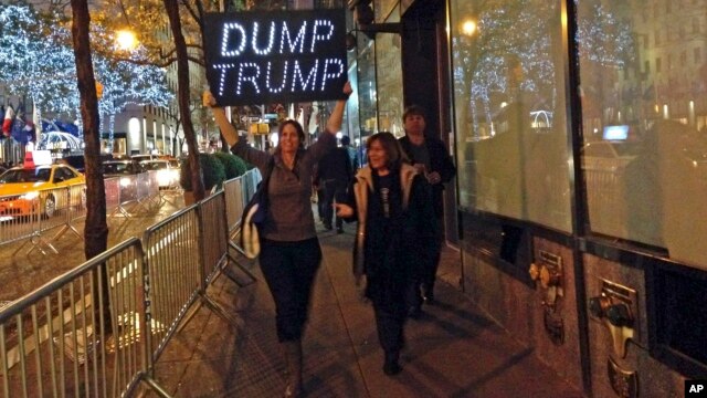 Unas manifestantes protestan por la presencia de Donald Trump en el probrama Saturday Night Live, con un letrero que dice "Boten a Trump".
