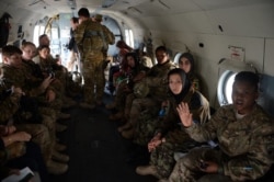 FILE - Afghan women and International Security Assistance Force female soldiers sit inside a helicopter for a ride with the Afghan Air Force at the Kabul International Airport, in Kabul, March 7, 2013.