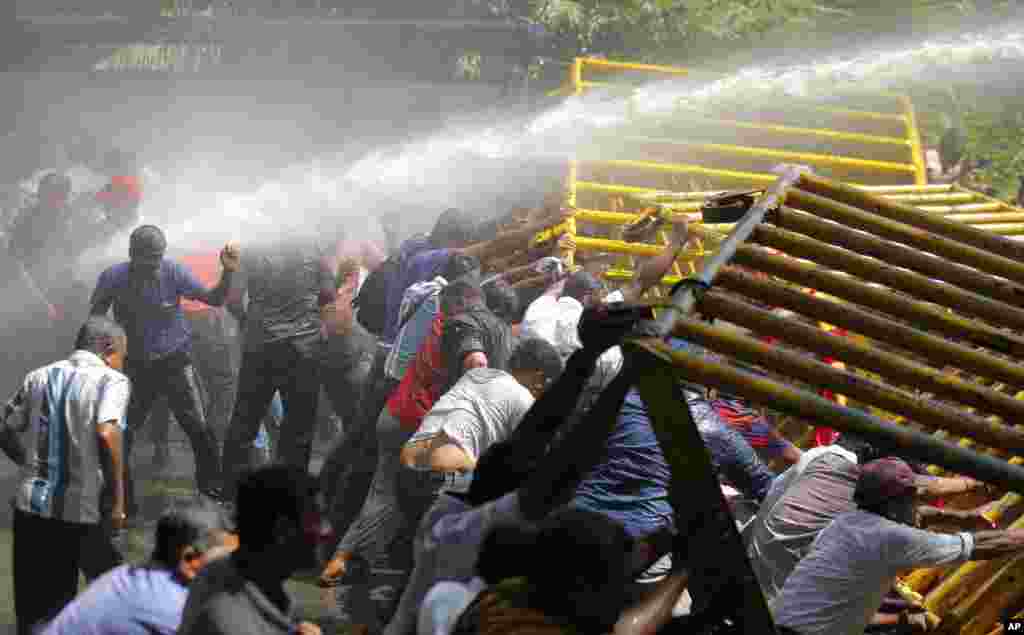 Sri Lankan port workers backed by the Marxist political party, attempt to remove a barricade as police fire water cannon during a protest march near the presidential secretariat in Colombo, Sri Lanka.