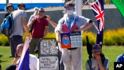 FILE - Anti-vaccination protesters demonstrate outside Melbourne Park after Serbia's Novak Djokovic was believed to be held at an immigration detention hotel in Melbourne, Australia, Jan. 15, 2022.