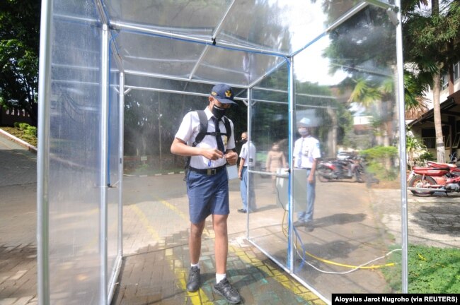 Seorang siswa yang memakai masker pelindung masuk ke dalam ruang desinfeksi di Salatiga, Provinsi Jawa Tengah, 13 Juli 2020. (Foto: Antara via Reuters)