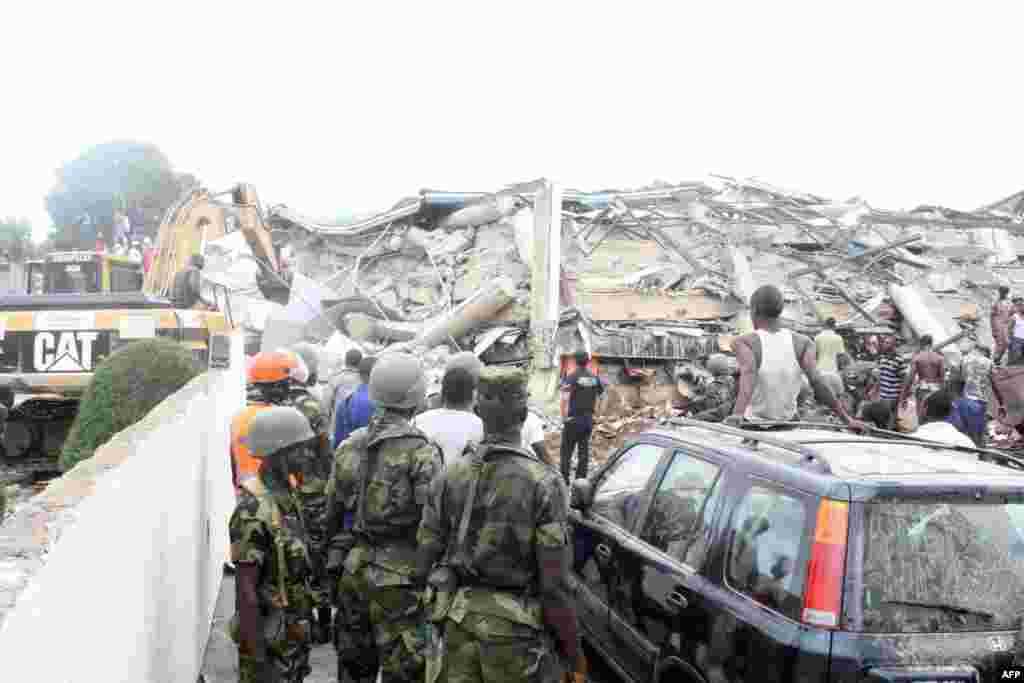 People look at an excavator clearing the rubble on the scene of a six-story shopping center that collapsed in Accra, November 7, 2012.