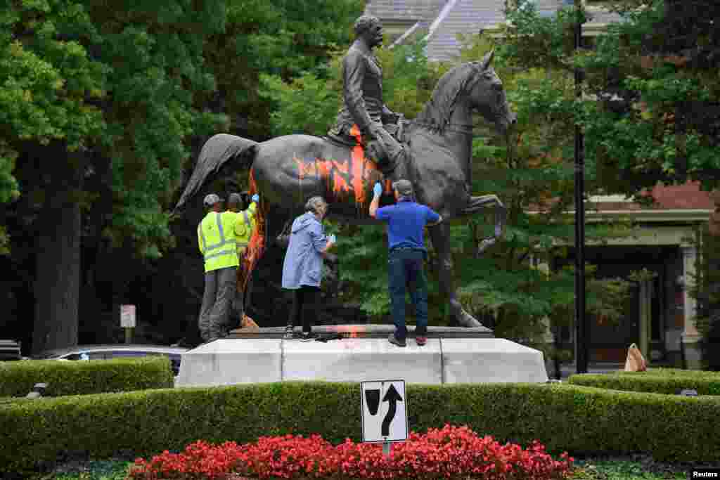 Para pekerja membersihkan cat dan coretan pada monumen patung pemimpin pasukan Konfederasi John B. Castleman yang jadi korban vandalisme di kota Louisville, Kentucky.