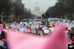 With a pink hat in the foreground, demonstrators march on Pennsylvania Avenue during the Women's March in Washington, Jan. 19, 2019.