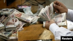An employee counts money at a bank in Cairo, Egypt, Sept. 4, 2014. 
