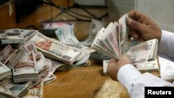 An employee counts money at a bank in Cairo, Egypt, Sept. 4, 2014. 
