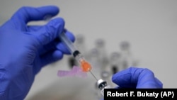 FILE - A pharmacy technician loads a syringe with Pfizer's COVID-19 vaccine, Tuesday, March 2, 2021, at a mass vaccination site at the Portland Expo in Portland, Maine. 