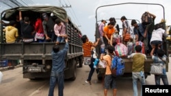 Cambodian workers ride on military trucks as they prepare to cross the Thai-Cambodia border at Aranyaprathet in Sa Kaew, June 15, 2014.