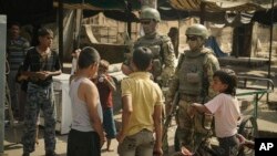 FILE - In this Sept. 15, 2017, photo, Russian soldiers escorting a group of journalists stand guard as children gather, in Deir el-Zour , Syria. 