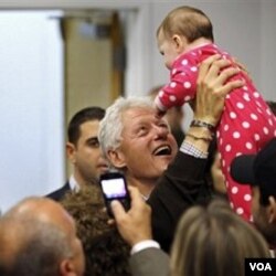 Mantan Presiden Clinton mengangkat seorang bayi saat berkampanye bagi kandidat John Hall di Harriman, New York.