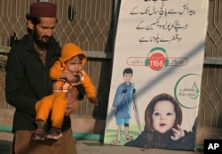 A man with a child leaves after polio vaccination of his child at a health center, in Peshawar, Pakistan, Jan. 24, 2022.