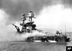 FILE - In this file image provided by the U.S. Navy, crewmen of the USS Nevada still fight flames on the battleship, battered in the Japanese aerial attack on Pearl Harbor on Dec. 7, 1941.