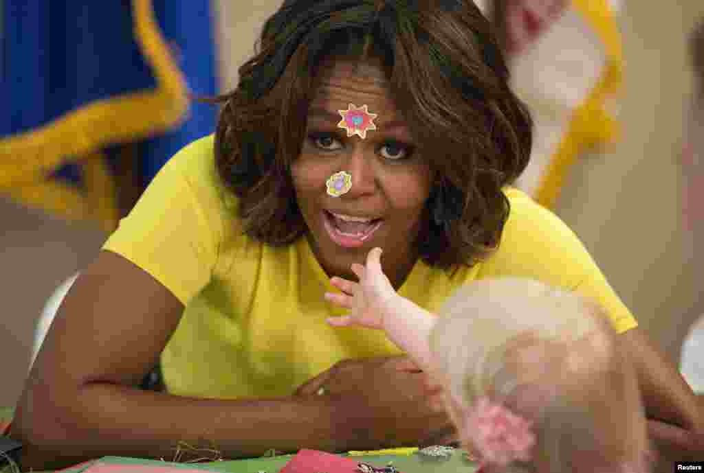 U.S. first lady Michelle Obama has stickers put on her face by 20-month-old Lily Oppelt during a visit with children at the Fisher House at Walter Reed National Military Medical Center in Bethesda, Maryland, April 14, 2014.