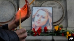 A woman holds a candle next to a portrait of slain television reporter Viktoria Marinova during a vigil at the Liberty Monument in Ruse, Bulgaria, Oct. 8, 2018.