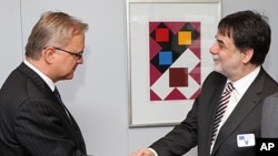 Hungary's chief negotiator with the IMF and the EU, Tamas Fellegi, right, shakes hands with European Commissioner for Economic and Monetary Affairs Olli Rehn, left, in Brussels, January 20, 2012.