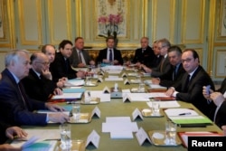 French President Francois Hollande (right) is surrounded by ministers and officials as they hold a defense council at the Elysee Palace in Paris, April 21, 2017.