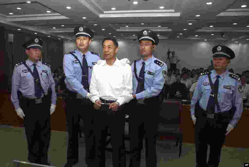 In this photo released by the Jinan Intermediate People's Court, Bo Xilai is handcuffed and held by police officers as he stands at the court in Jinan, in eastern China's Shandong province, Sept. 22, 2013.