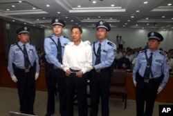 FILE - In this photo released by the Jinan Intermediate People's Court, fallen politician Bo Xilai, center, is handcuffed and held by police officers as he stands at the court in Jinan, in eastern China's Shandong province, Sept. 22, 2013.