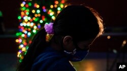 FILE - In this Dec. 17, 2020, file photo a girl chooses a toy at a holiday toy giveaway held at Los Angeles Boys & Girls Club in the Lincoln Heights neighborhood of Los Angeles. According to a survey from The Associated Press-NORC Center for Public Affair