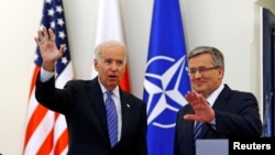 U.S. Vice President Joe Biden (L) waves as he meets Polish President Bronislaw Komorowski in Warsaw March 18, 2014.