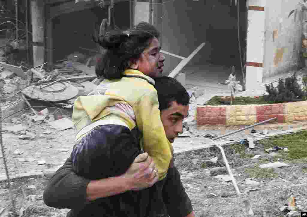 A man carries his sister who was wounded in a government airstrike in Ansari, in Aleppo, Feb. 3, 2013. 