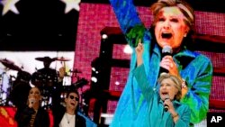Calon presiden AS dari Partai Demokrat, Hillary Clinton, didampingi penyanyi Jennifer Lopez dan Marc Anthony, di atas panggung konser Get Out The Vote di Bayfront Park Amphitheater, Miami (29/10). (AP/Andrew Harnik)