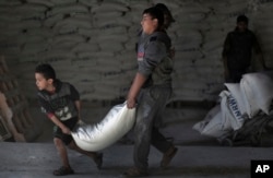 FILE - Palestinians receive UNRWA food aid at a U.N. warehouse at Shati refugee camp, in Gaza City, Jan. 14, 2018.