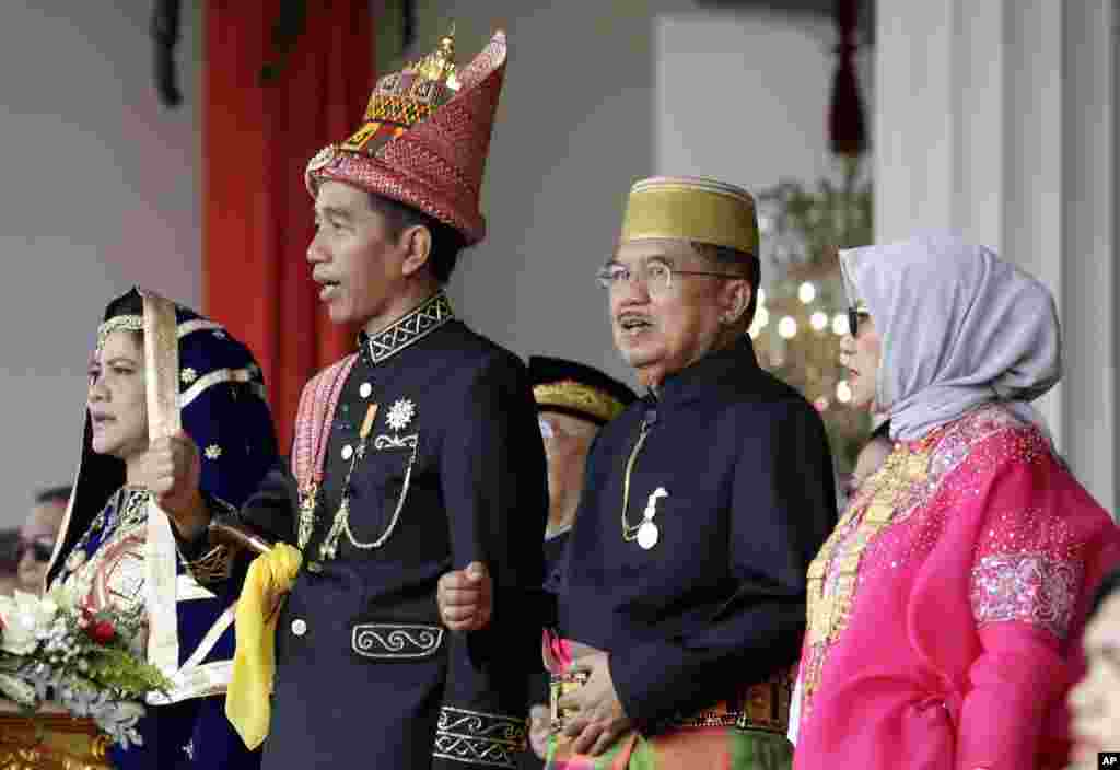 Presiden Joko Widodo (kedua dari kiri) dan Ibu Negara Iriana (kiri), Wakil Presiden Jusuf Kalla (kedua dari kanan) dan istri, Mufidah Kalla (kanan) menyanyikan lagu nasional dalam upacara peringatan Ulang Tahun ke-73 Republik Indonesia di Istana Merdeka di Jakarta, Jumat, 17 Agustus 2018. (Foto: AP)