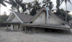 Dua rumah di Kampung Renteng, Desa Sumber Wuluh, Lumajang, tampak terendam pasir yang disebabkan oleh guguran awan panas dari erupsi Gunung Semeru yang terjadi pada 4 Desember 2021. Foto diambil pada 7 Desember 2021. (Foto: VOA/Indra Yoga)