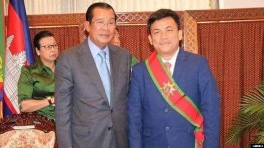 រូបលោក កុយ គួង (ស្តាំ) អ្នកនាំពាក្យក្រសួងការបរទេស និងសហប្រតិបតិ្តការអន្តរជាតិ ឈរថតរូបជាមួយលោក ហ៊ុន សែន នាយករដ្ឋមន្រ្តីនៃប្រទេសកម្ពុជា។ (រូបថតពីទំព័រហ្វេសប៊ុក Koug Koy)