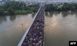 FILE - A Honduran migrant caravan heads to the U.S., on the Guatemala-Mexico international border bridge in Ciudad Hidalgo, Chiapas state, Mexico, Oct. 20, 2018.