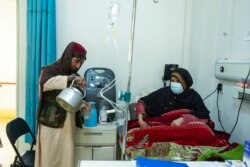 FILE - An Afghan man prepares tea for a relative being treated for COVID-19 in the emergency ward of the Afghan-Japan Hospital, in Kabul, Afghanistan, Dec. 9, 2021.