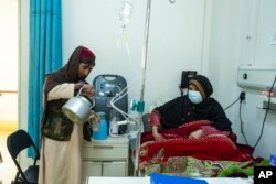 FILE - An Afghan man prepares tea for a relative being treated for COVID-19 in the emergency ward of the Afghan-Japan Hospital, in Kabul, Afghanistan, Dec. 9, 2021.