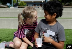 FILE - Camper Gracie, left, leans toward Nugget during an activity at the Bay Area Rainbow Day Camp in El Cerrito, Calif., July 11, 2017.