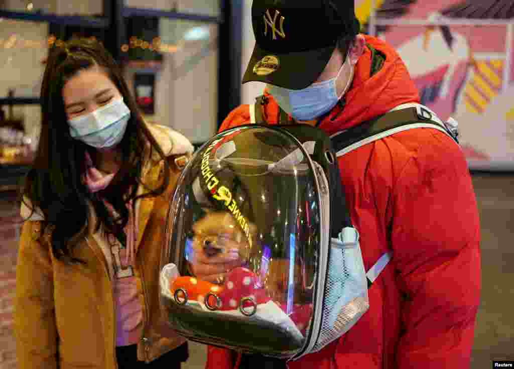 A man wearing a protective face mask pets his puppy inside a backpack while walking through the city center during a lockdown to curb the spread of the coronavirus outbreak in Sydney, Australia.