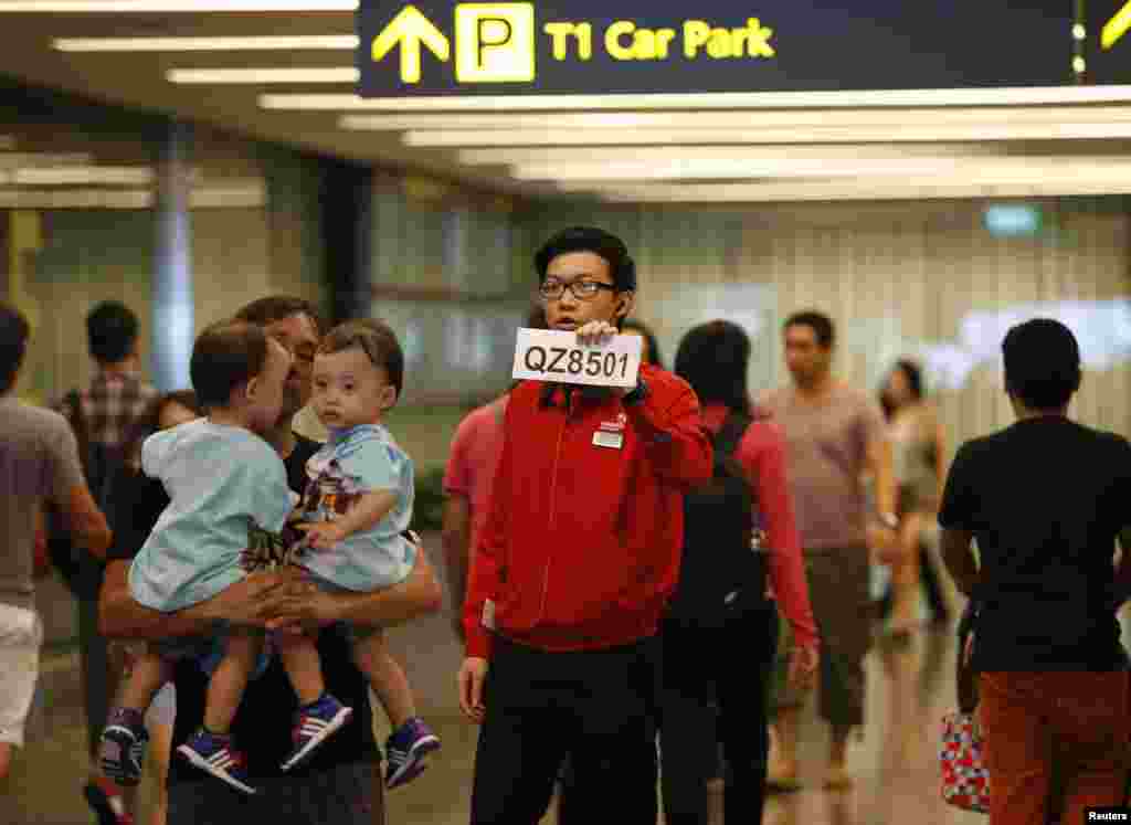 A airport staff member directs relatives of passengers of AirAsia flight QZ 8501 from Indonesian city of Surabaya to Singapore, at Changi Airport in Singapore, Dec. 28, 2014.