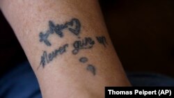 Art shown on the arm of Dana Zzyym that reads "Never give up" October 27, 2021. Zzyym said the art helps them remember goals to carry out in life. (AP Photo/Thomas Peipert)