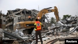Un secouriste se tient sur des gravats d'un immeuble effondré dans le district de l’île Victoria à Lagos, Nigeria, 5 novembre 2013