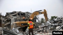 Une pelleteuse creuse dans les décombres d'un bâtiment effondré dans le quartier de Victoria Island à Lagos, le 5 novembre 2013. 