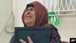 Umm Zine Nceri, the mother of 36-year-old Adel Hammami, who threatened to expose fraud within Tunisia's old ruling RCD party and was brutally killed, cries as she holds a photo of Hammami, in Sidi Bouzid, Tunisia, August 2011
