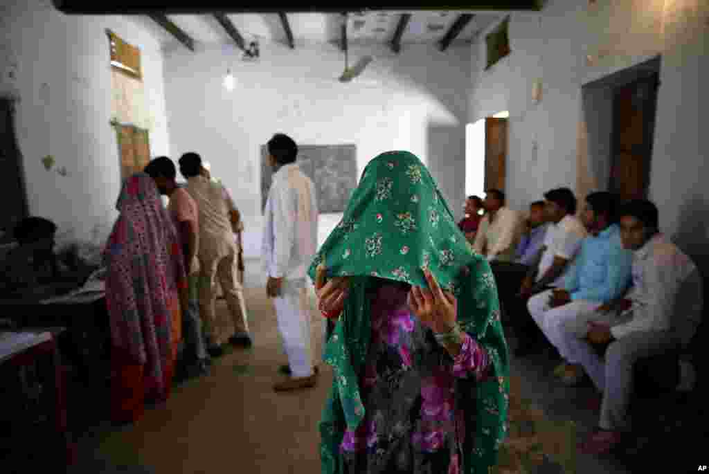 A woman holds a veil over her face and waits for her identity card to be checked before she is allowed to vote in Chandeni, in the northern Indian state of Haryana, April 10, 2014.