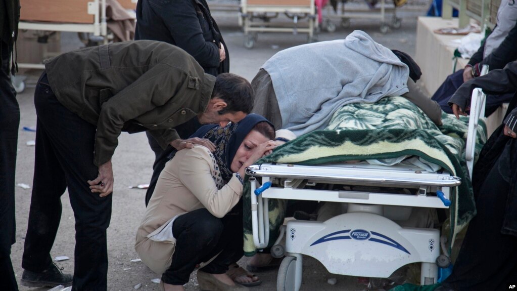 In this photo provided by Tasnim News Agency, relatives weep over the body of an earthquake victim, in Sarpol-e-Zahab, western Iran, Nov. 13, 2017. 